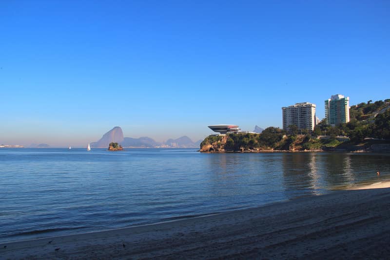 Praia do Ingá, em Niterói, com o Museu de Arte Contemporânea e o Pão de Açúcar ao fundo, em dia de céu azul
